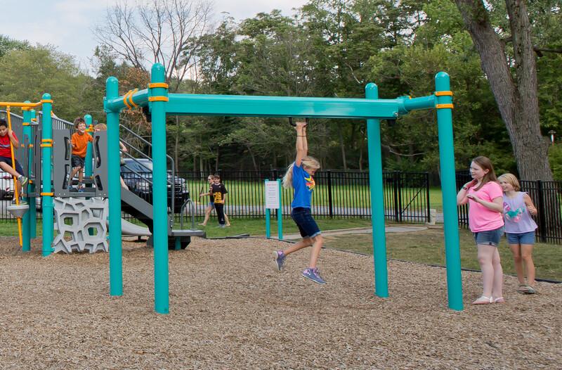 girls rides on a playground zipline while two friends watch