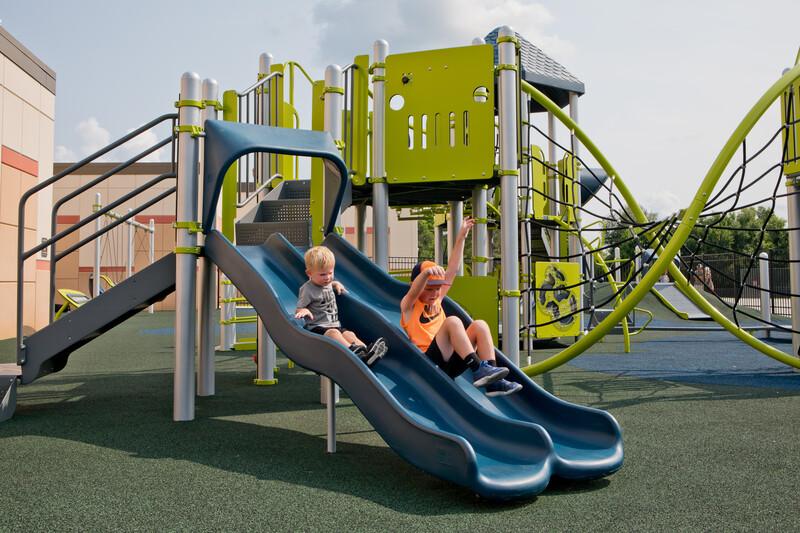 Two boys riding Double Wave slide