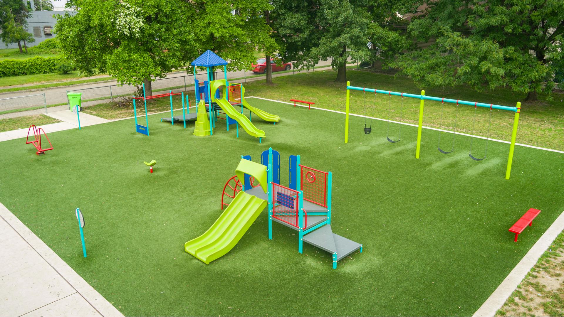 Elevated view of a play area with synthetic grass and many playground activities.
