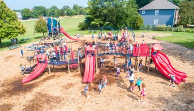 Scores of children from River Woods Elementary playing on their playground on a sunny day.