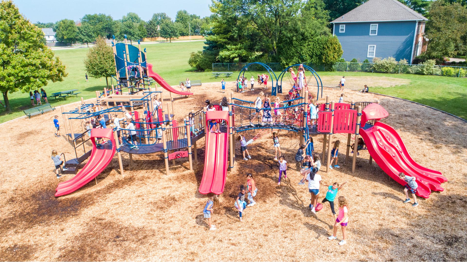 Scores of children from River Woods Elementary playing on their playground on a sunny day.