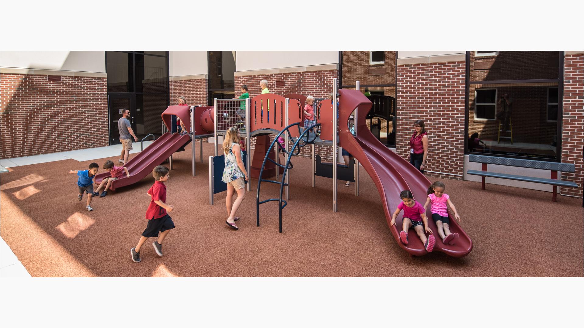 Parents watch their children on PlayShaper play structure in courtyard.