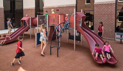 Parents watch their children on PlayShaper play structure in courtyard.