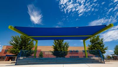 Ground view up of a cantilever shade covering a outdoor concrete step seating area.