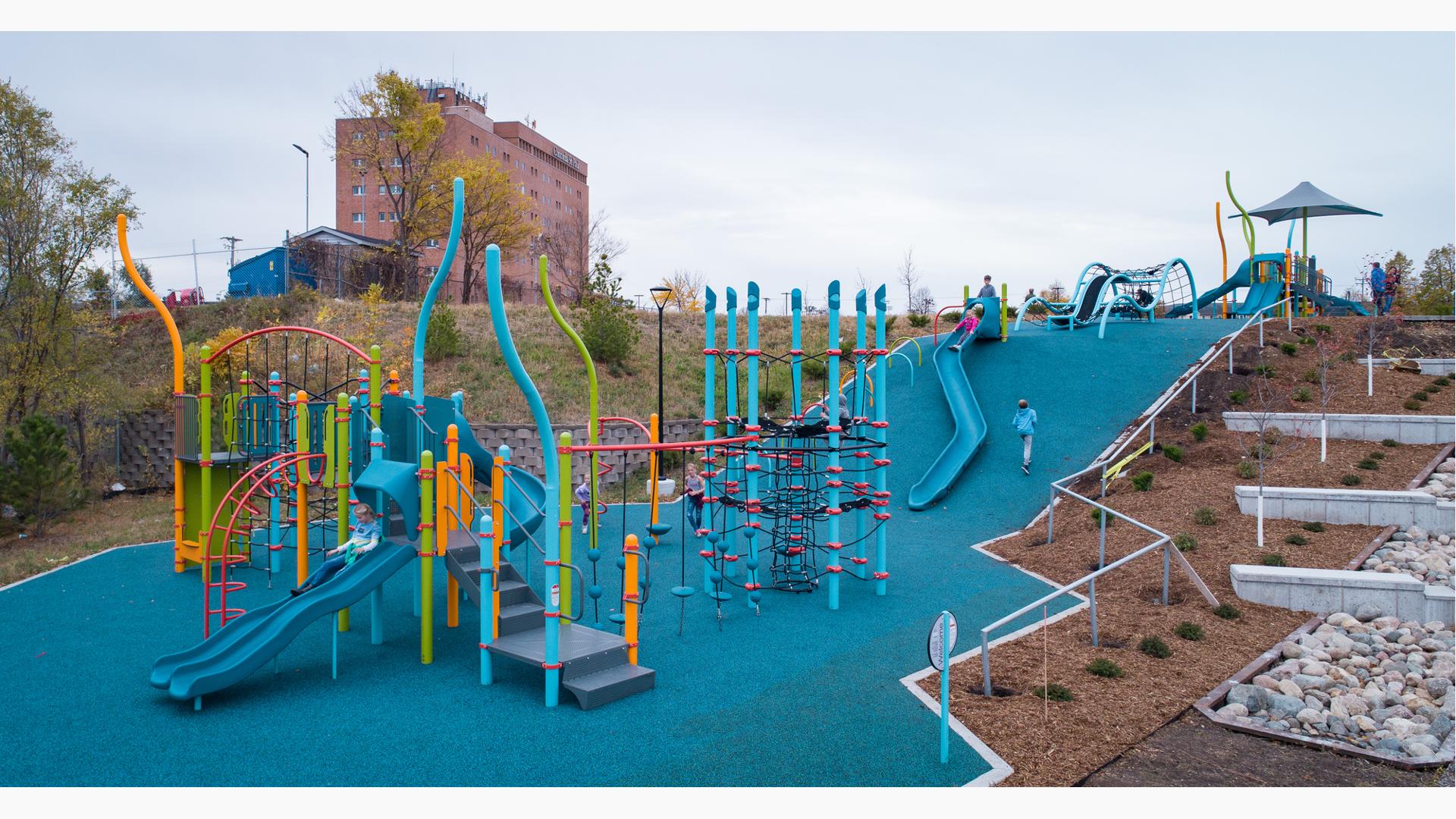 Midway Peace Park, St. Paul, MN. A multi-level PlayBooster® playground structure with climbers, slides and activity panels along with integrated shade.