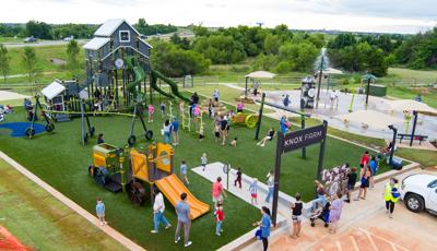 Elevated view of families playing at a farm themed playground next to a splash pad.