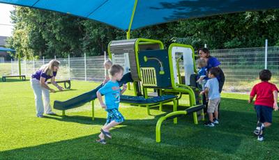 Blue & green playsmart play structure being surrounded by kids from Smart Start Childcare Center.