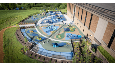 Elevated view of a large half moon shaped play area divided by fencing for specific play areas based on age designed with a religious theme of the creation of the world.