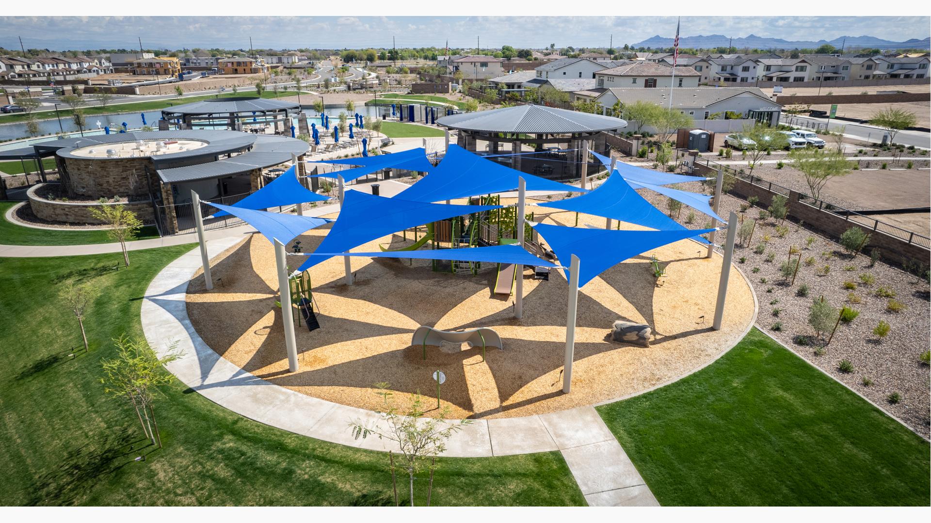 Elevated view of a circular playground area with multiple large blue triangle shade sales overhead.