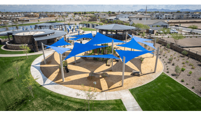 Elevated view of a circular playground area with multiple large blue triangle shade sales overhead.