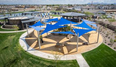 Elevated view of a circular playground area with multiple large blue triangle shade sales overhead.