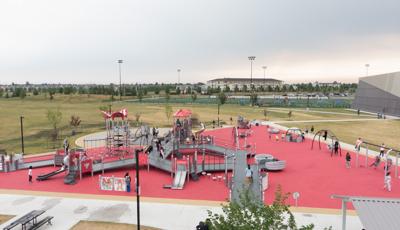 Elevated view of a triangular shape play area. One large play structure is connected by accessible ramps and bridges for all abilities. Swing sets and other accessible playground activities sit on the perimeter of the play area.