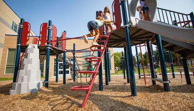 Girl in jean shorts climbing to the top of Square Loop Incline Climber