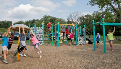 Children playing on playground at Baden Academy Charter School featuring a a Flywheel® spinner and Track Ride