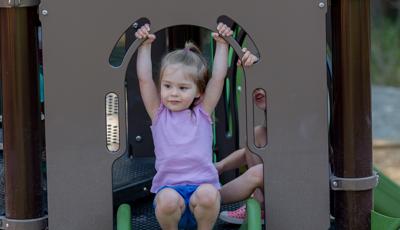 Girl sitting on top of Play shaper slide.