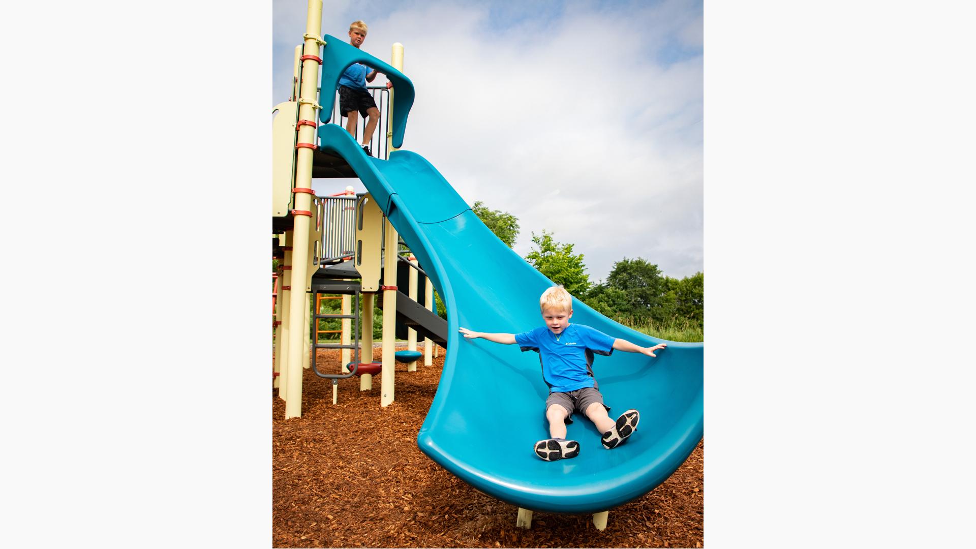 A boy descends a bright blue Alpine Slide.