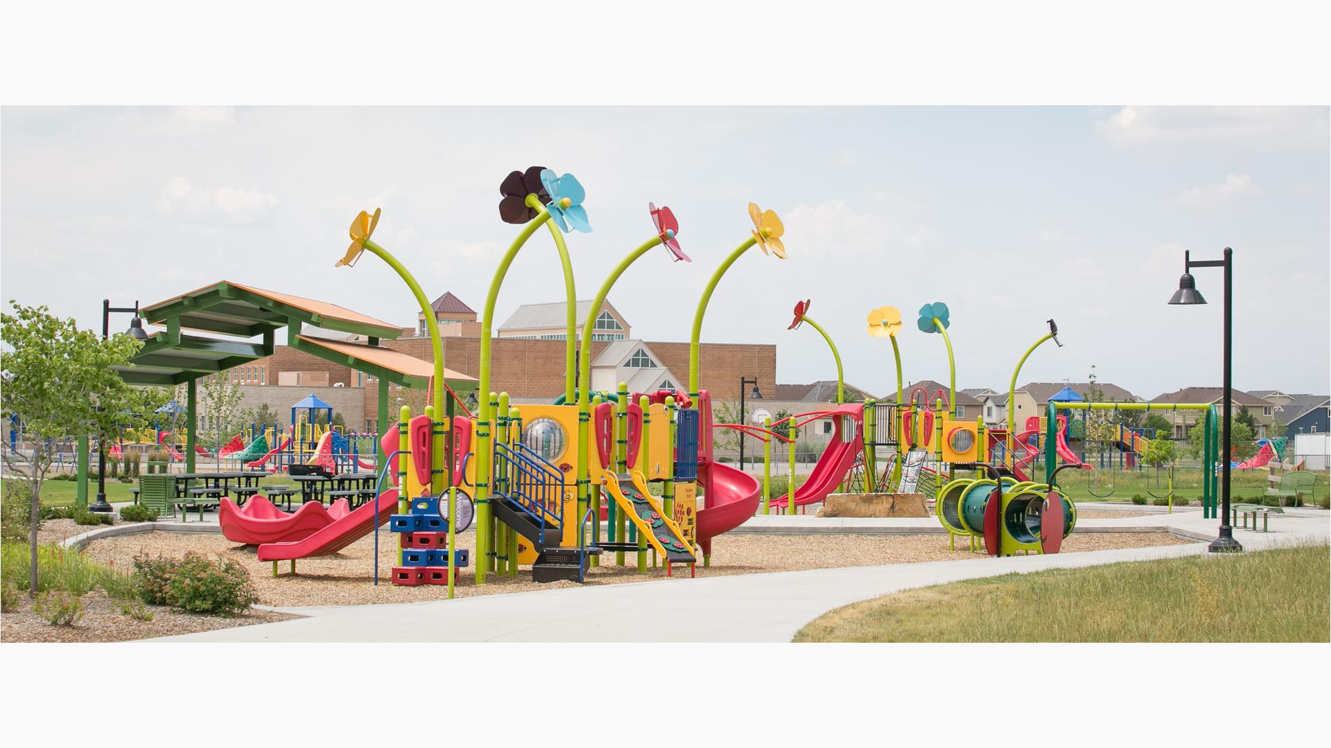 New custom Spring-themed playground with big flowers towering over the play structures, reaching up toward the sky. Bug, Bee, and catapillar-themed details add life.