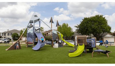 Children play on a mountain themed play structure at an neighborhood park with an additional smaller play structure for younger children with similar color scheme.