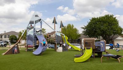 Children play on a mountain themed play structure at an neighborhood park with an additional smaller play structure for younger children with similar color scheme.