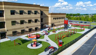 Elevated view of of a first responders themed playground outside a elementary school building.