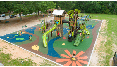 Children play on a nature themed play structure with concrete realistic designed tree trunks, tunnels, and climbers.