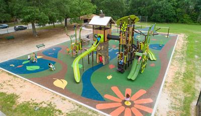 Children play on a nature themed play structure with concrete realistic designed tree trunks, tunnels, and climbers.