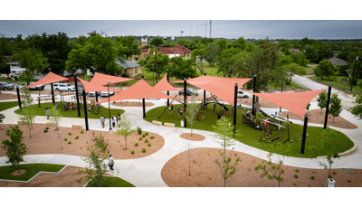 Elevated view of multiple burnt orange shade sails covering a large playground play area.