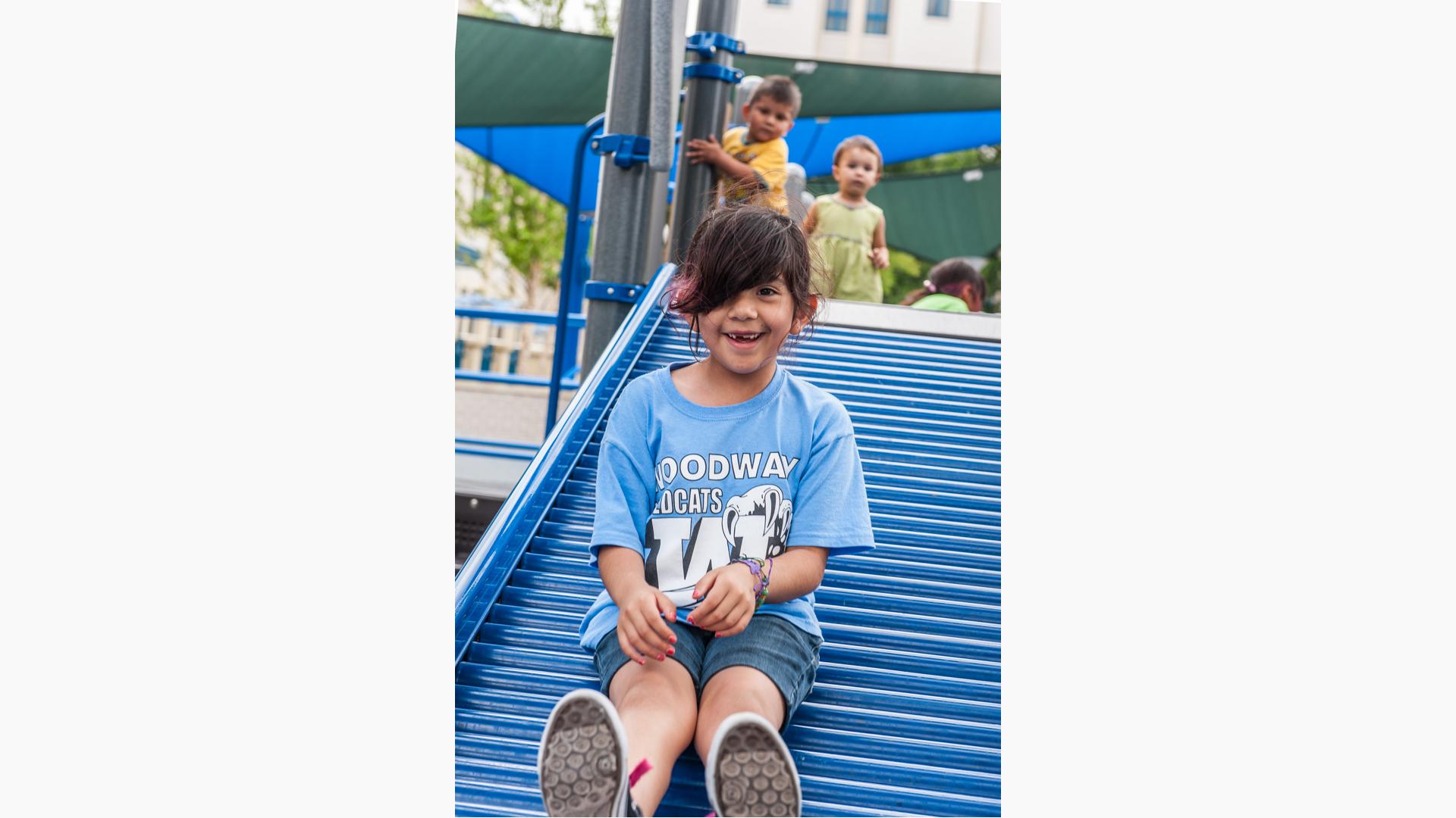 Girl smiling as she sits on Roller Slide