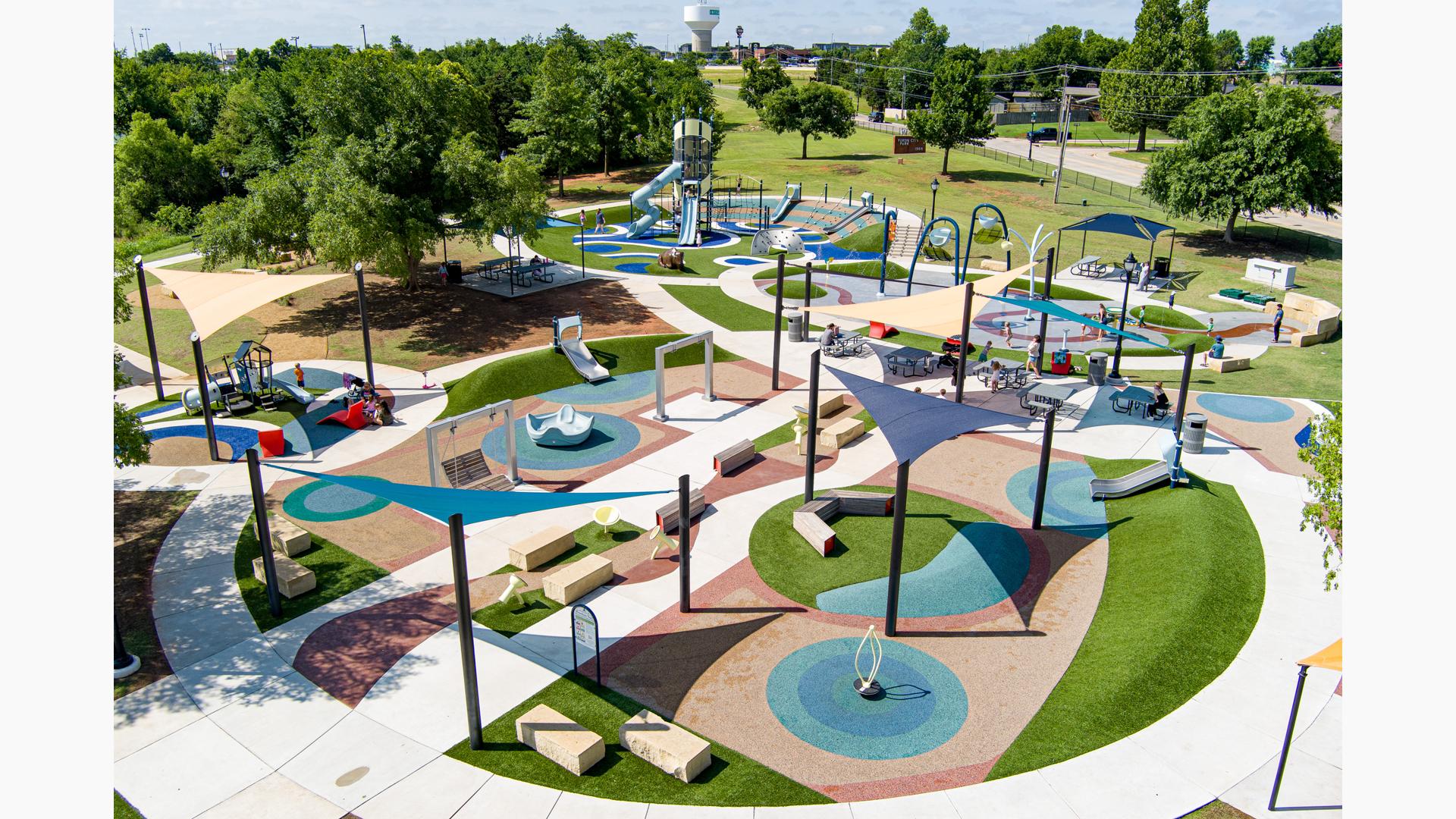 Elevated view of scattered play activities incorporated into the typography of small park hills and a splash pad.