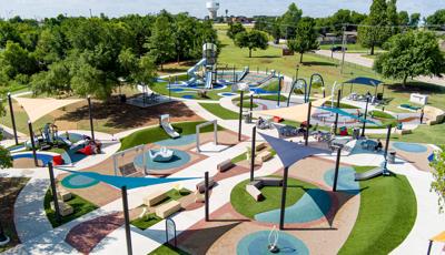 Elevated view of scattered play activities incorporated into the typography of small park hills and a splash pad.