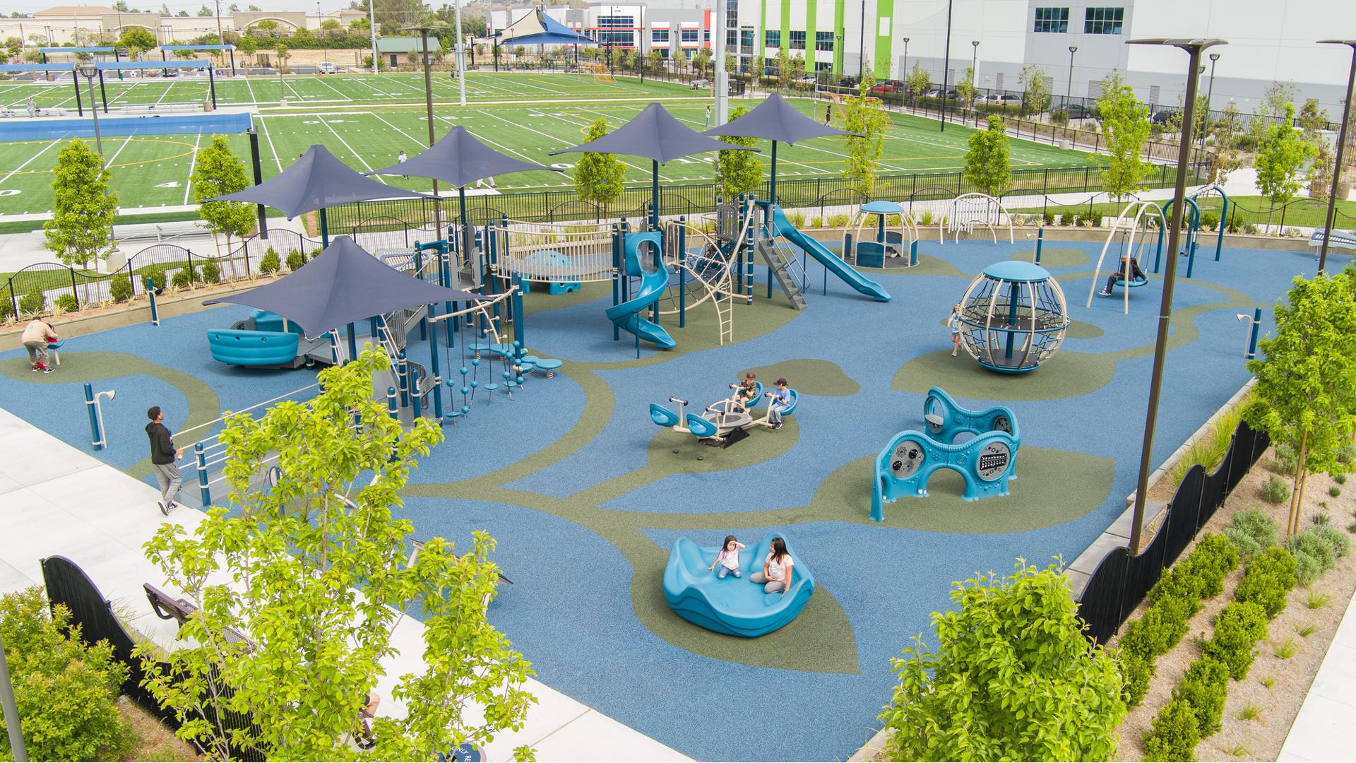 Elevated view of a triangular shaped play area colored in blue and greens with inclusive play activities for all abilities.