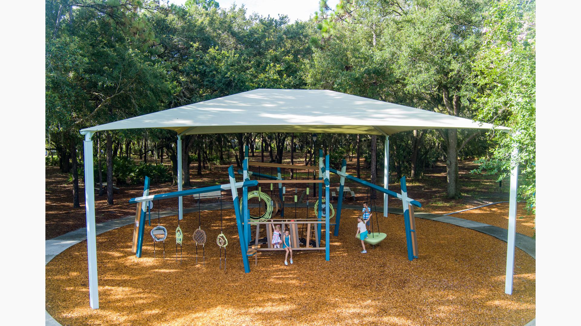 Elevated view of a large shade system over play structures with playing children.