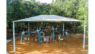 Elevated view of a large shade system over play structures with playing children.