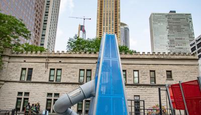 Girl standing on trampoline next to blue custom play structure