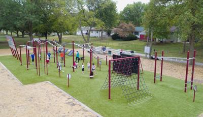 Adult and kids are ready for the challenges of Howdershell FitCore® Park. Parked on a patch of green grass, men stand under different freestanding structures to test their agility.