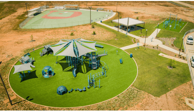 Elevated view of a circular play area with playground a secondary rectangular play area with fitness obstacle course equipment and a inclusive baseball field for all abilities.