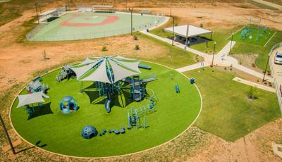 Elevated view of a circular play area with playground a secondary rectangular play area with fitness obstacle course equipment and a inclusive baseball field for all abilities.