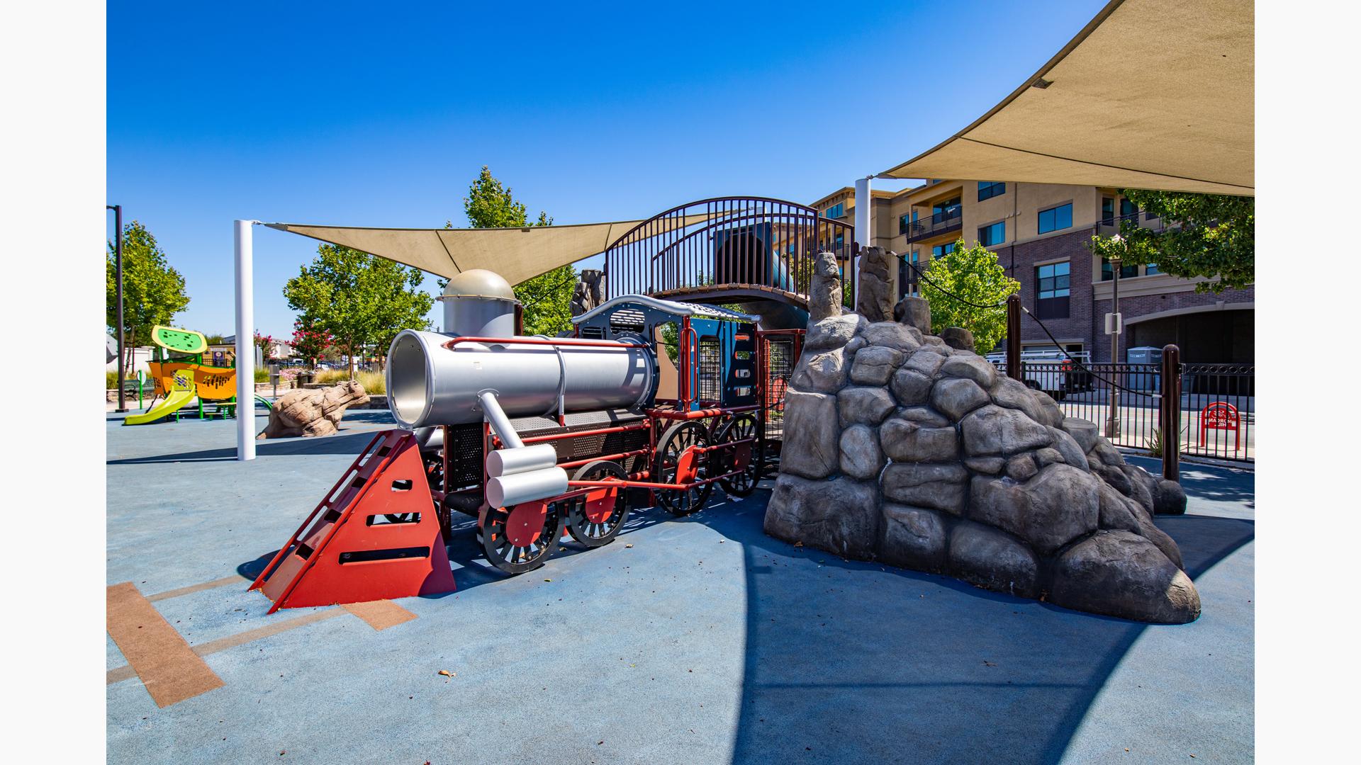 Custom trained-themed playground going through rocky tunnel.