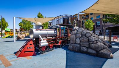 Custom trained-themed playground going through rocky tunnel.