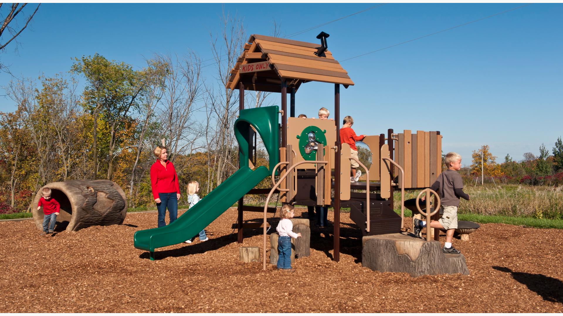 Mom watches children play on nature-inspired PlayShaper play structure on a sunny day.