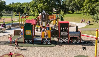 Reverend Dr. Martin Luther King, Jr. Park children play on a custom choo choo train featuring a slide on the caboose. A memorial stands at the center of the park connected to bridges, clmbers, and more.