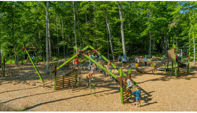 Elevated view of a park playground nestled next to a lush line of trees.