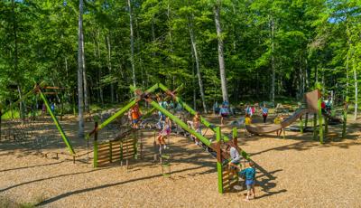 Elevated view of a park playground nestled next to a lush line of trees.