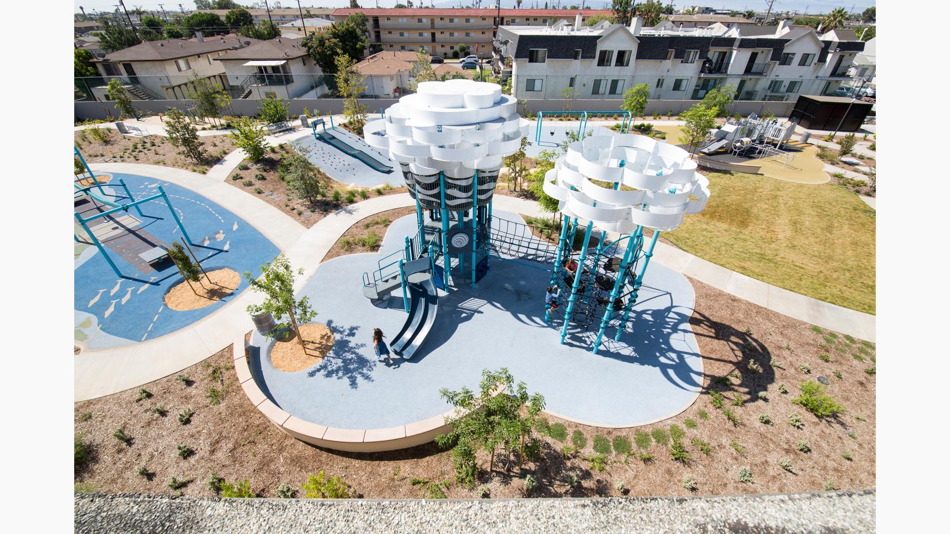 Aerial view of a nature themed playground with large white panels at the top of the two tower stuctures symbolizing large fluffy clouds.