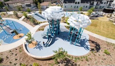 Aerial view of a nature themed playground with large white panels at the top of the two tower stuctures symbolizing large fluffy clouds.