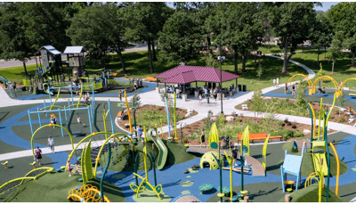 Elevated view of a large park play area with a nature inspired theme and a pavilion rest area with picnic tables.