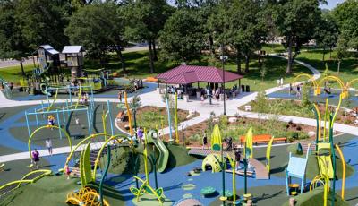 Elevated view of a large park play area with a nature inspired theme and a pavilion rest area with picnic tables.