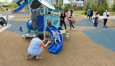 Boy happily rides down slide to woman