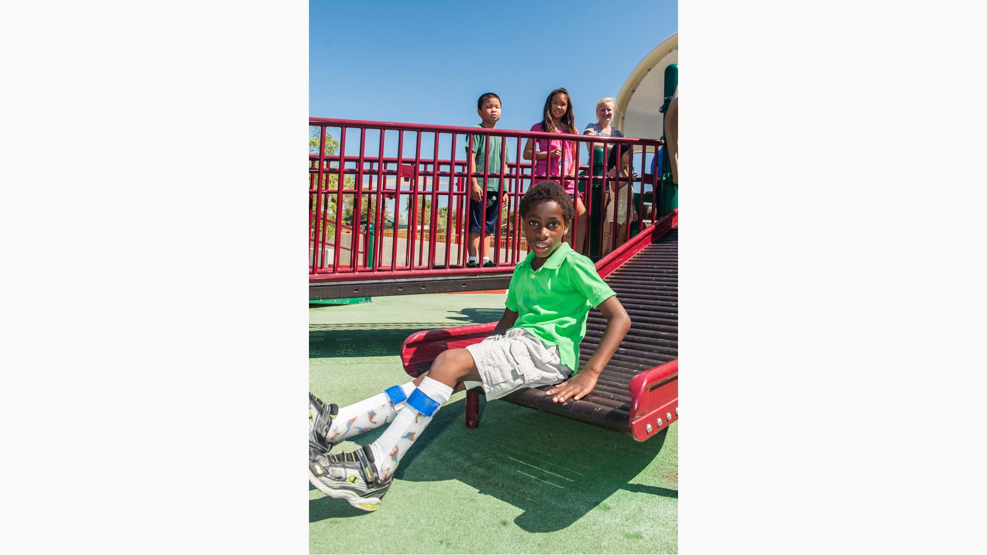 Boy in green shirt sitting on rollerslide