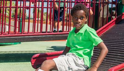 Boy in green shirt sitting on rollerslide